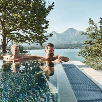 Wassersport Paar entspannt im Infinity-Pool mit Blick auf See und Berge im Sommer